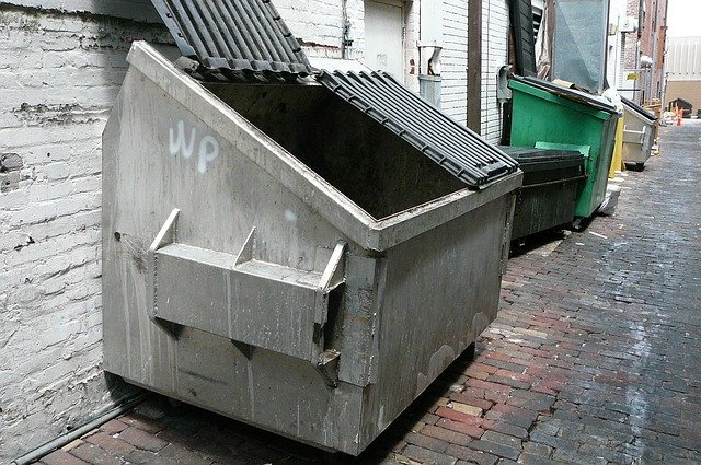 A grey dumpster in an alley