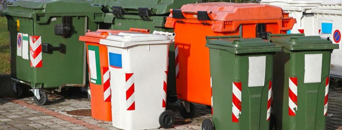 A grouping of garbage containers. There are many colors and sizes of containers for a variety of purposes.