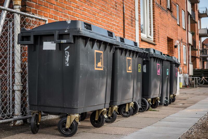 A row of small grey commercial garbage containers